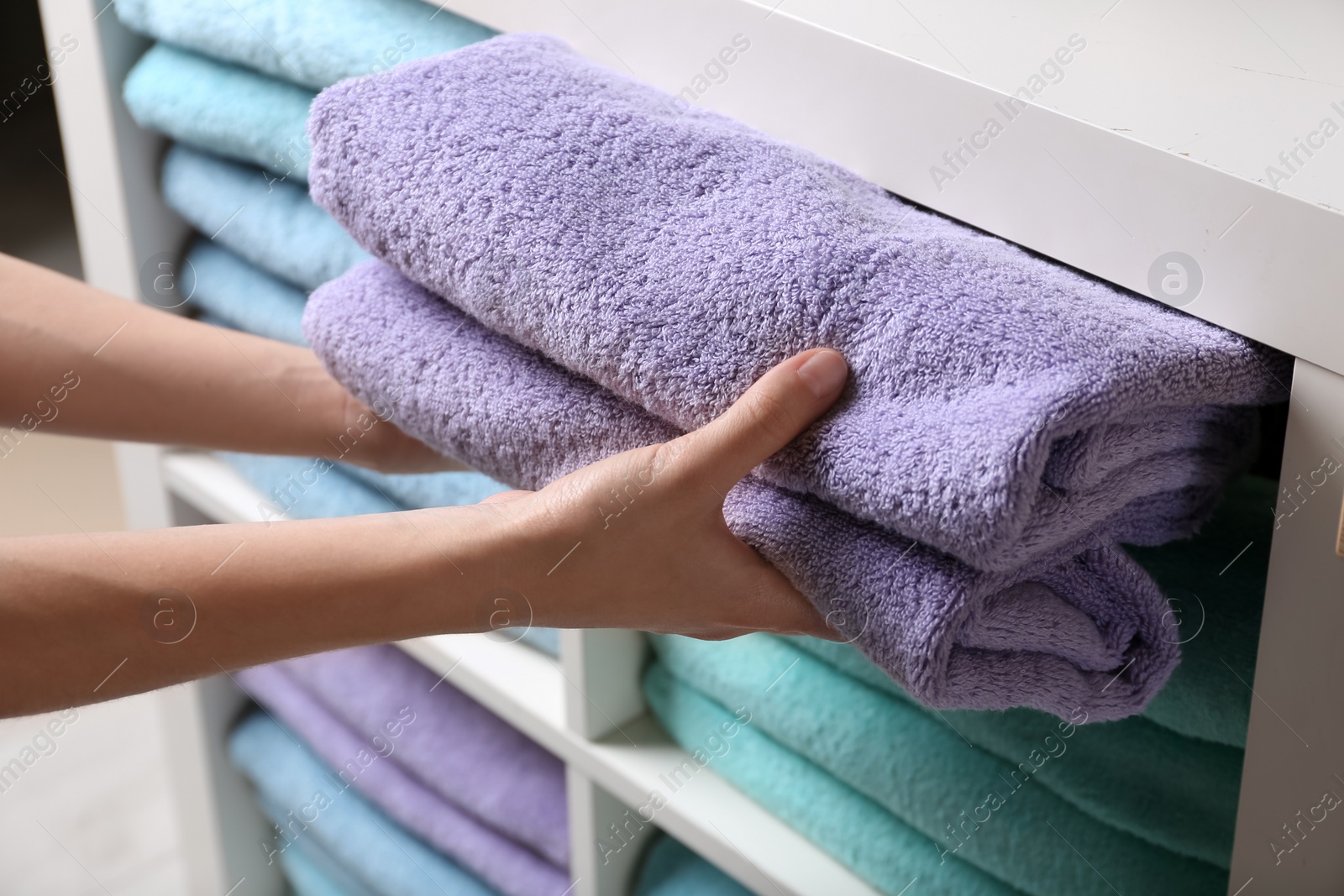 Photo of Woman putting towels on shelf, closeup view