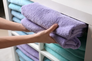 Photo of Woman putting towels on shelf, closeup view