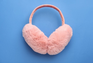 Stylish winter earmuffs on blue background, top view