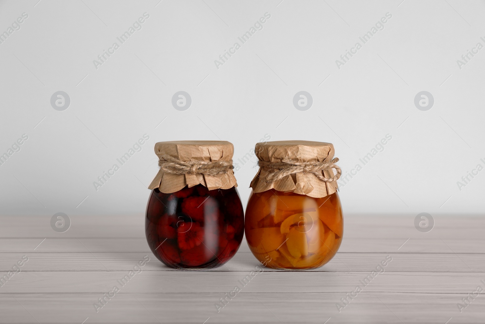 Photo of Jars with preserved fruit jams on white wooden table