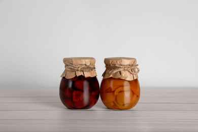 Jars with preserved fruit jams on white wooden table