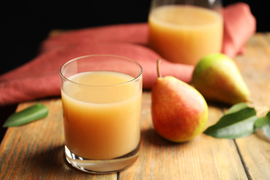 Fresh pear juice in glass and fruits on wooden table, closeup