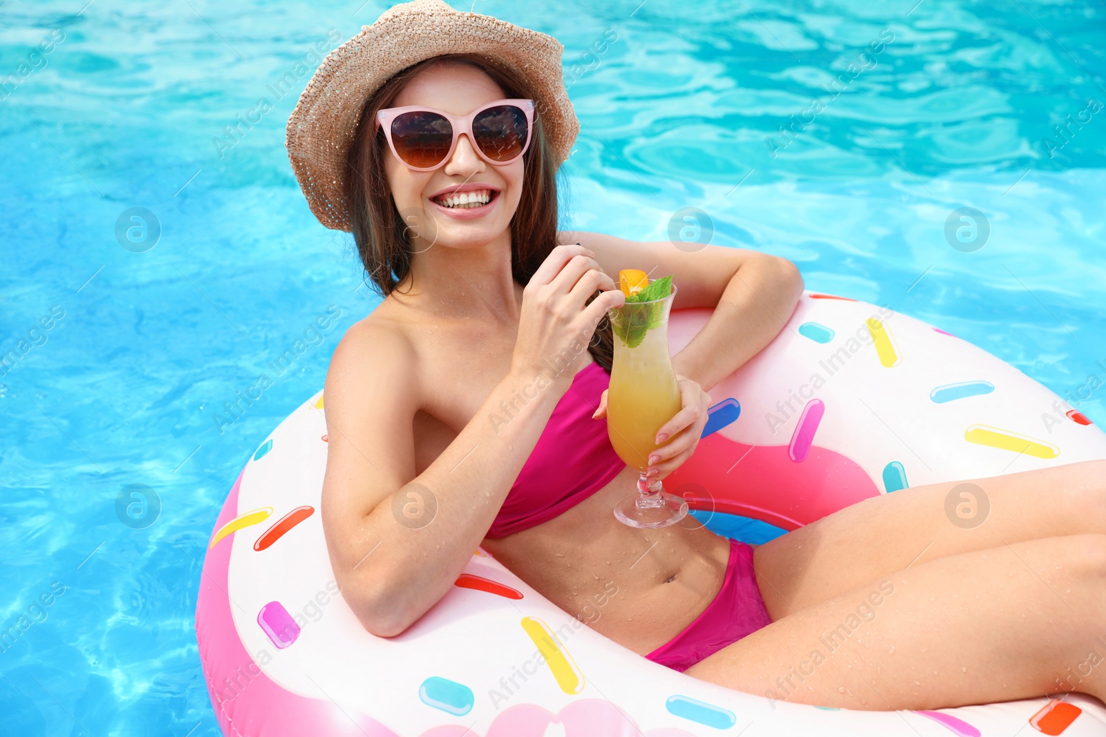 Photo of Young woman with cocktail in pool on sunny day