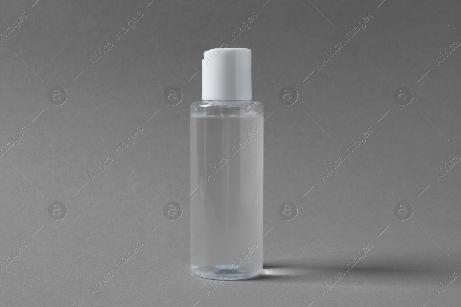 Photo of Transparent bottle with cosmetic product on grey background