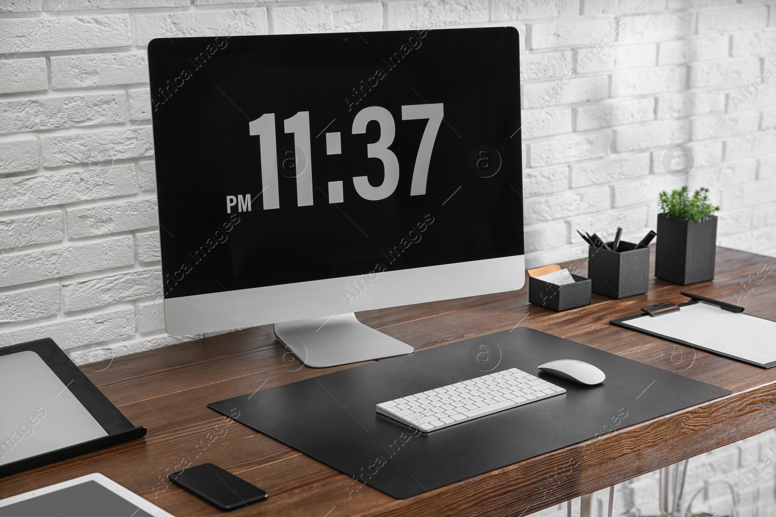 Photo of Modern workplace interior with computer and devices on table near brick wall