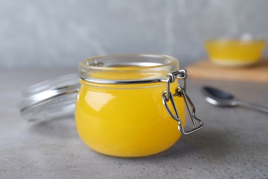 Glass jar of Ghee butter on grey table, closeup