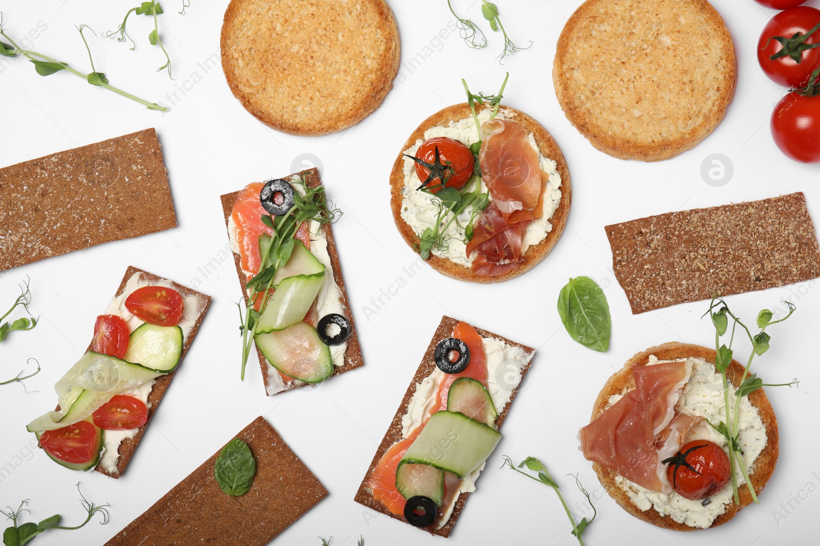 Photo of Tasty rusks and rye crispbreads with different toppings on white background, top view