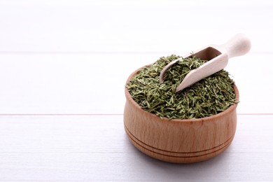 Photo of Bowl and scoop with dried thyme on white wooden table, closeup. Space for text