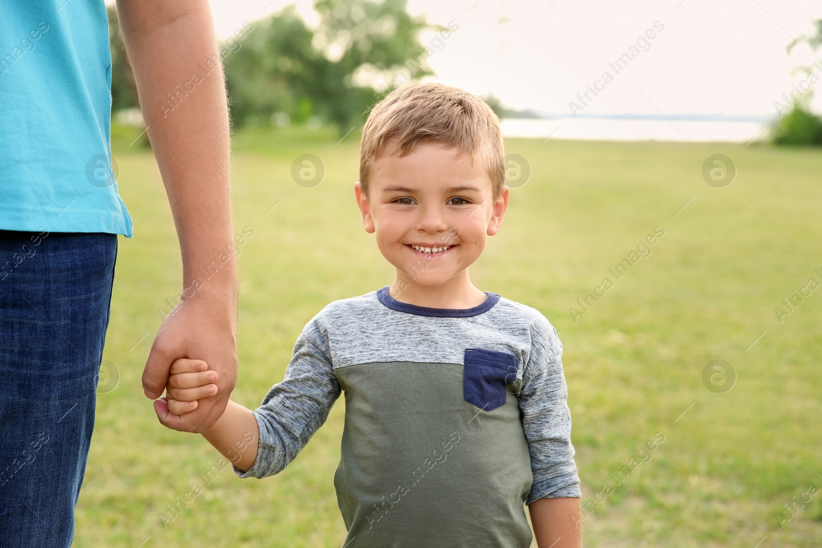 Photo of Man holding hands with his child outdoors. Happy family