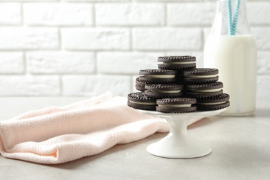 Photo of Cake stand with chocolate sandwich cookies on table against brick wall. Space for text