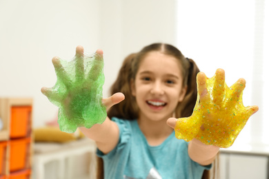 Preteen girl with slime in playroom, focus on hands