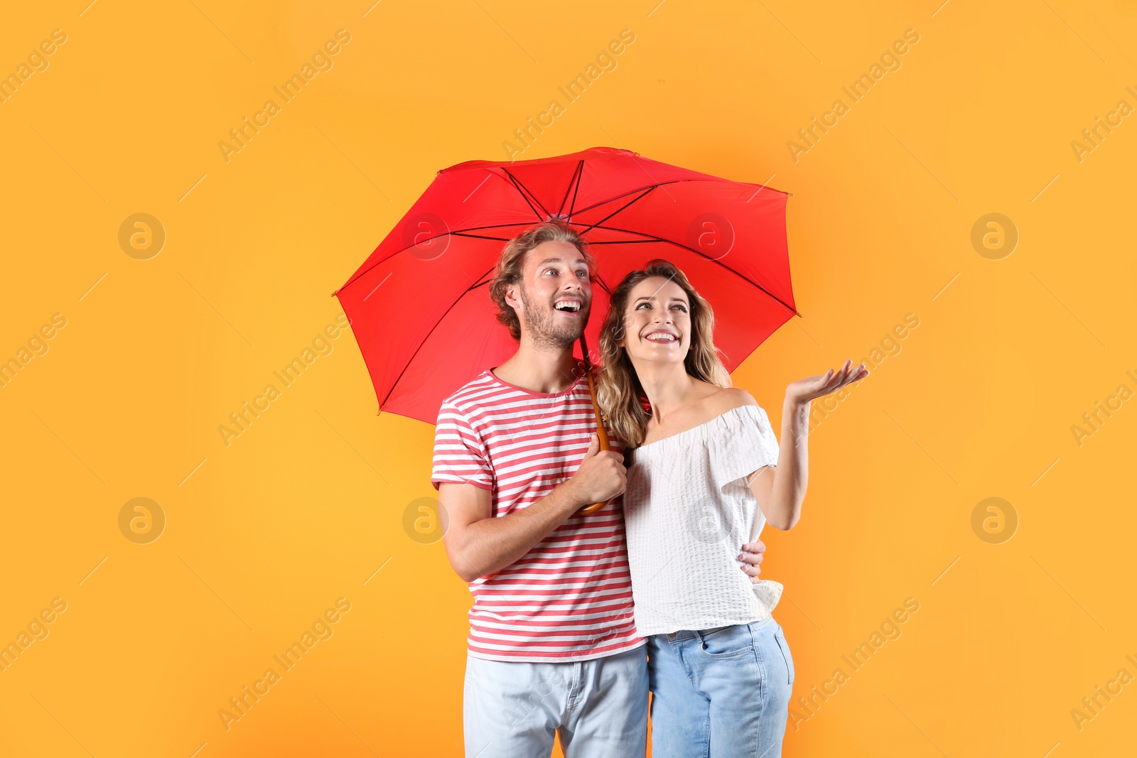 Photo of Couple with red umbrella on color background