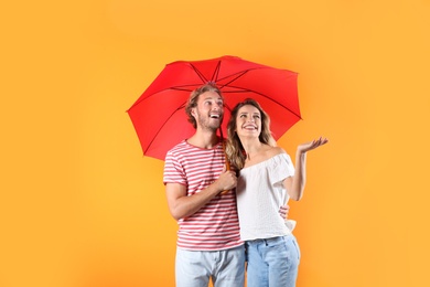 Photo of Couple with red umbrella on color background