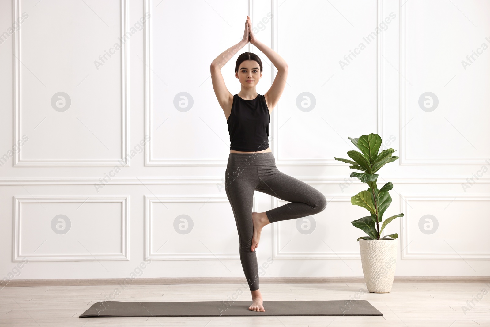 Photo of Girl practicing tree asana on mat in yoga studio. Vrksasana pose