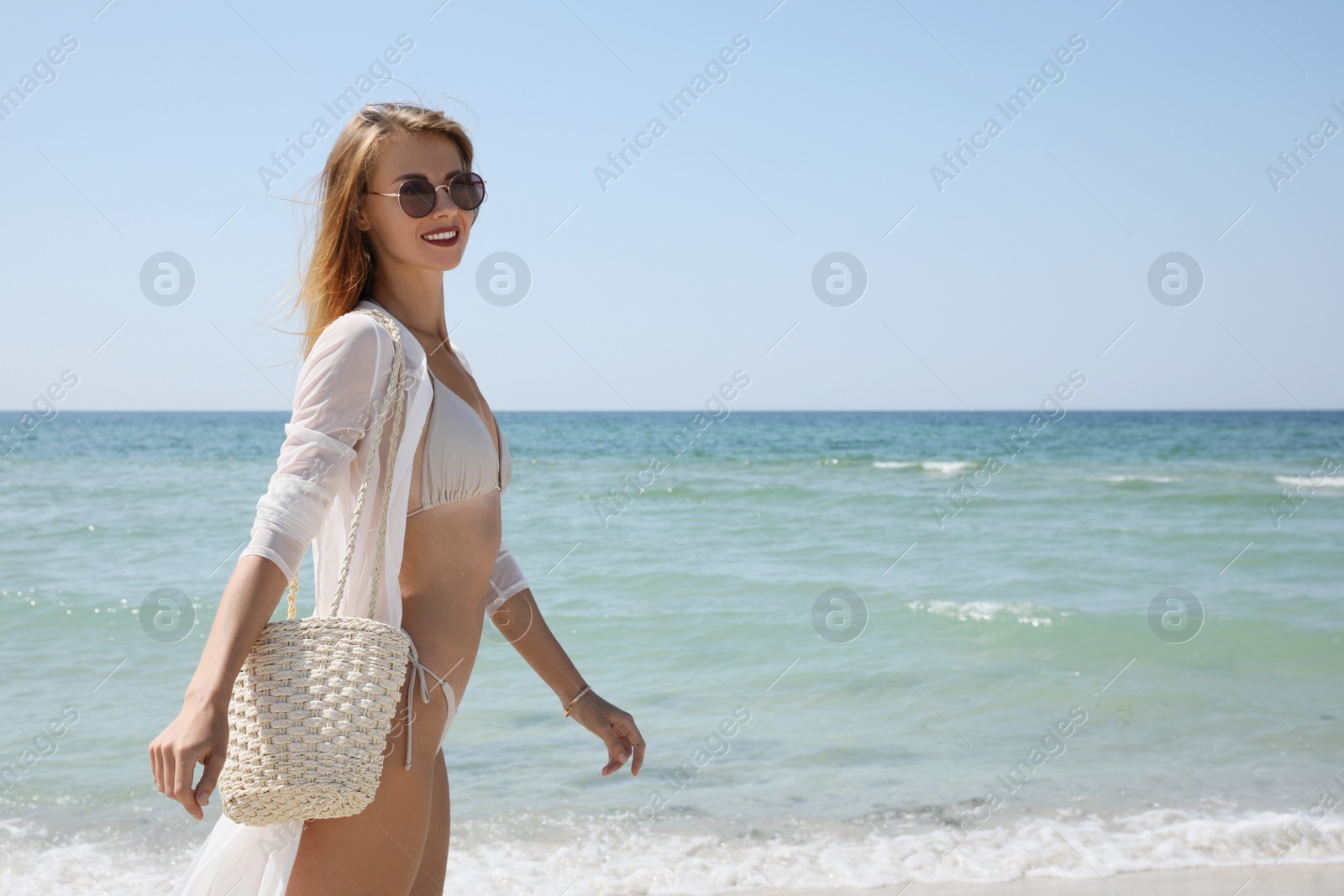 Photo of Beautiful woman with beach bag walking near sea