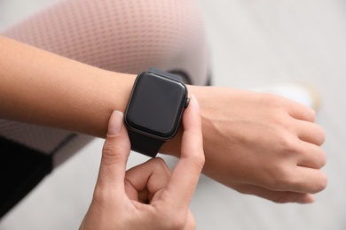 Woman checking stylish smart watch indoors, top view