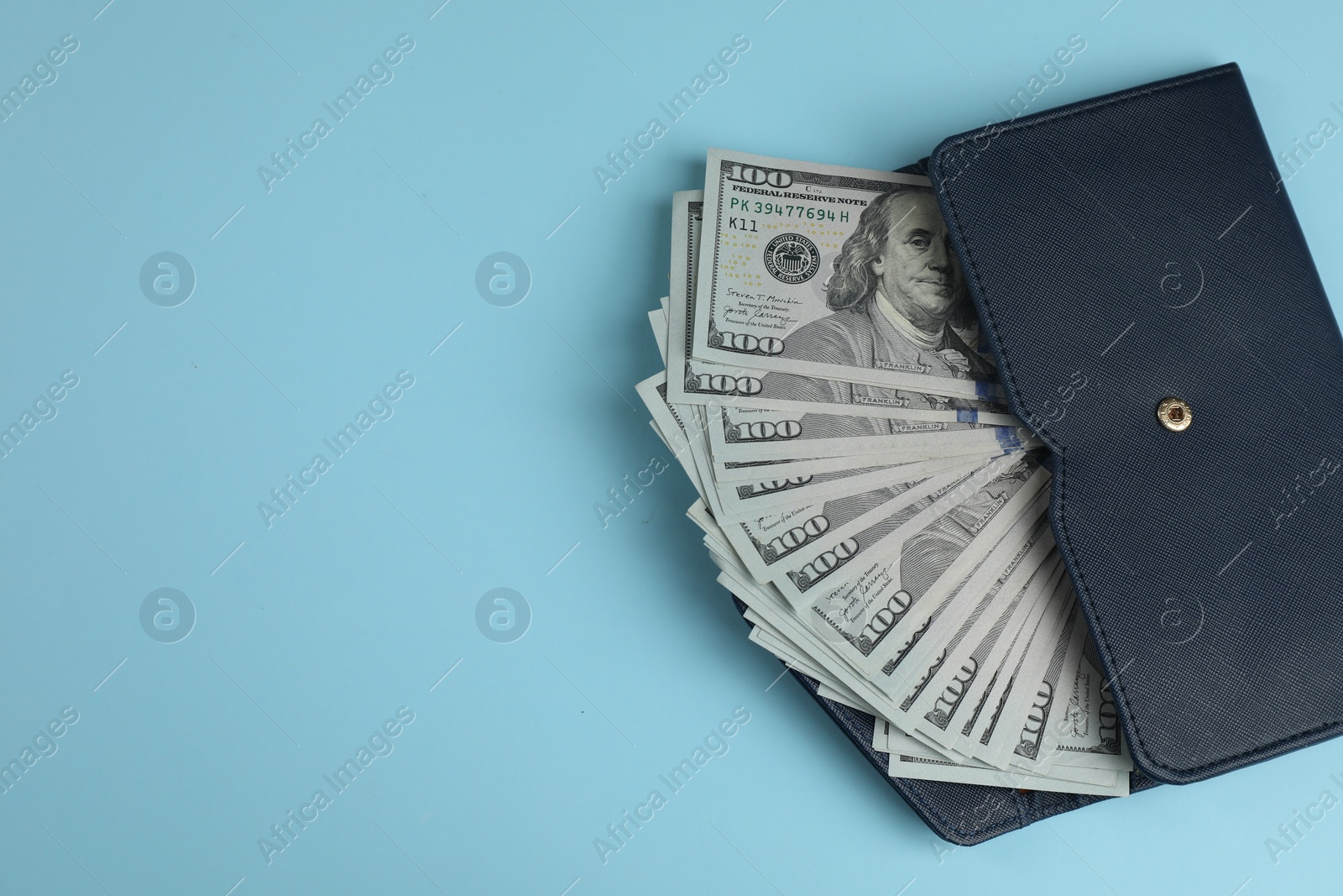 Photo of Money exchange. Wallet with dollar banknotes on light blue background, top view. Space for text