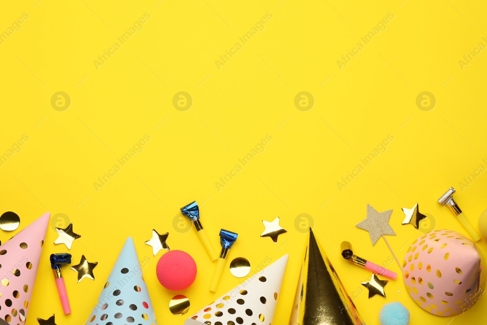 Photo of Flat lay composition with party hats and other festive items on yellow background. Space for text