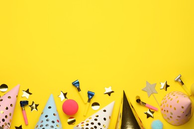 Photo of Flat lay composition with party hats and other festive items on yellow background. Space for text