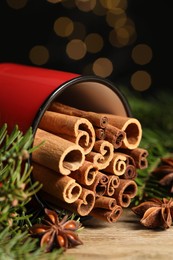 Many cinnamon sticks, anise stars and fir branches on wooden table, closeup