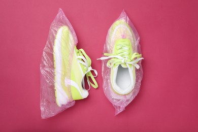 Sneakers in shoe covers on pink background, top view