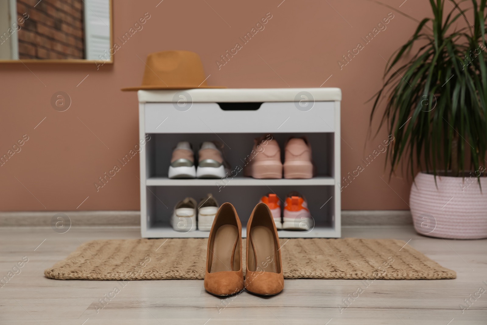 Photo of Shelving unit and stylish shoes on floor in hall