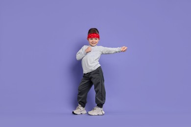 Photo of Happy little boy dancing on violet background