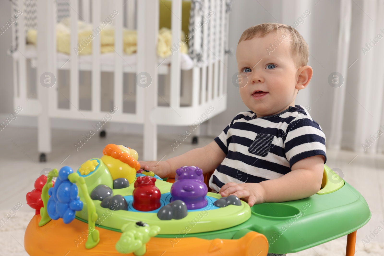 Photo of Portrait of cute baby with toy walker at home, space for text. Learning to walk