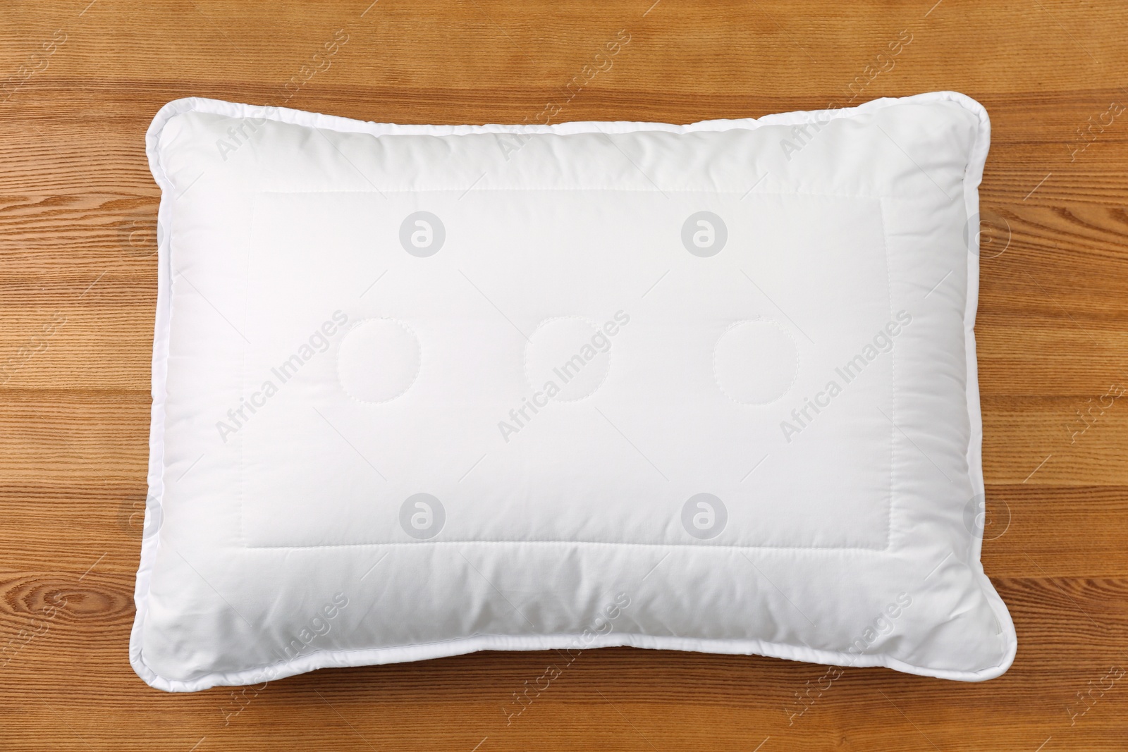 Photo of Soft bed pillow on wooden background, top view