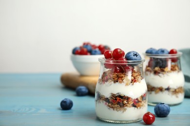 Delicious yogurt parfait with fresh berries on turquoise wooden table, space for text