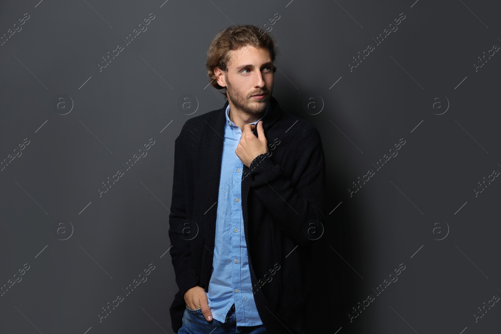 Photo of Handsome young man in shirt and warm sweater on dark background