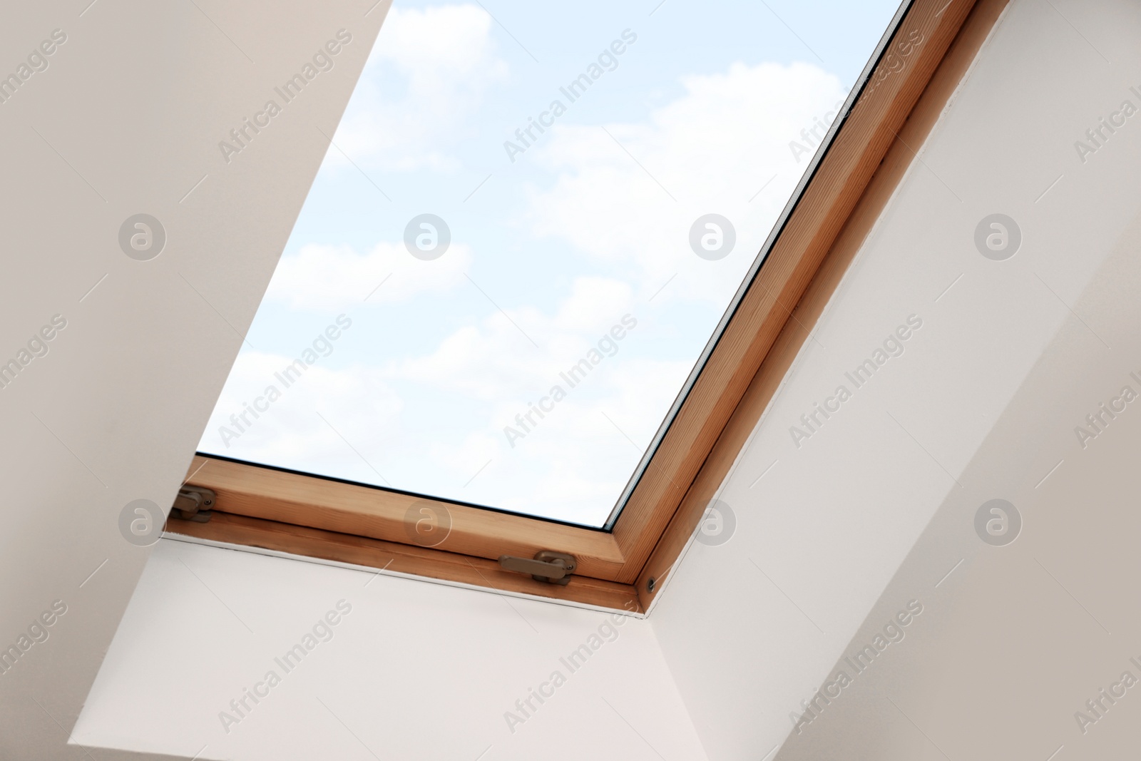 Photo of Skylight roof window on slanted ceiling in attic room, low angle view