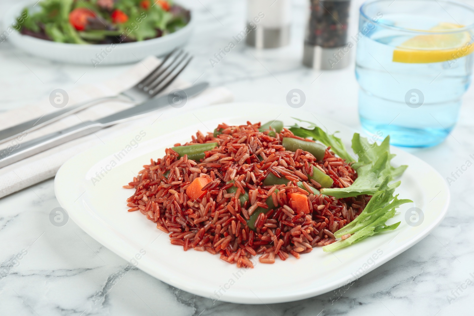 Photo of Tasty brown rice with vegetables on white marble table