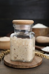 Photo of Leaven and ears of wheat on wooden table