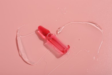 Skincare ampoule on pink surface with gel