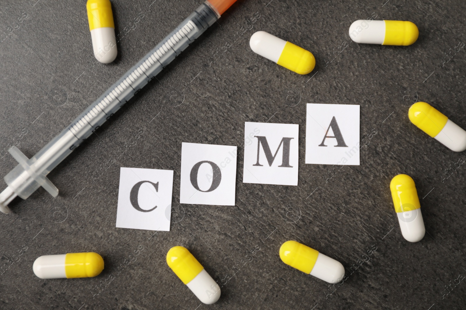 Photo of Word Coma of letters with syringe and pills on grey table, flat lay