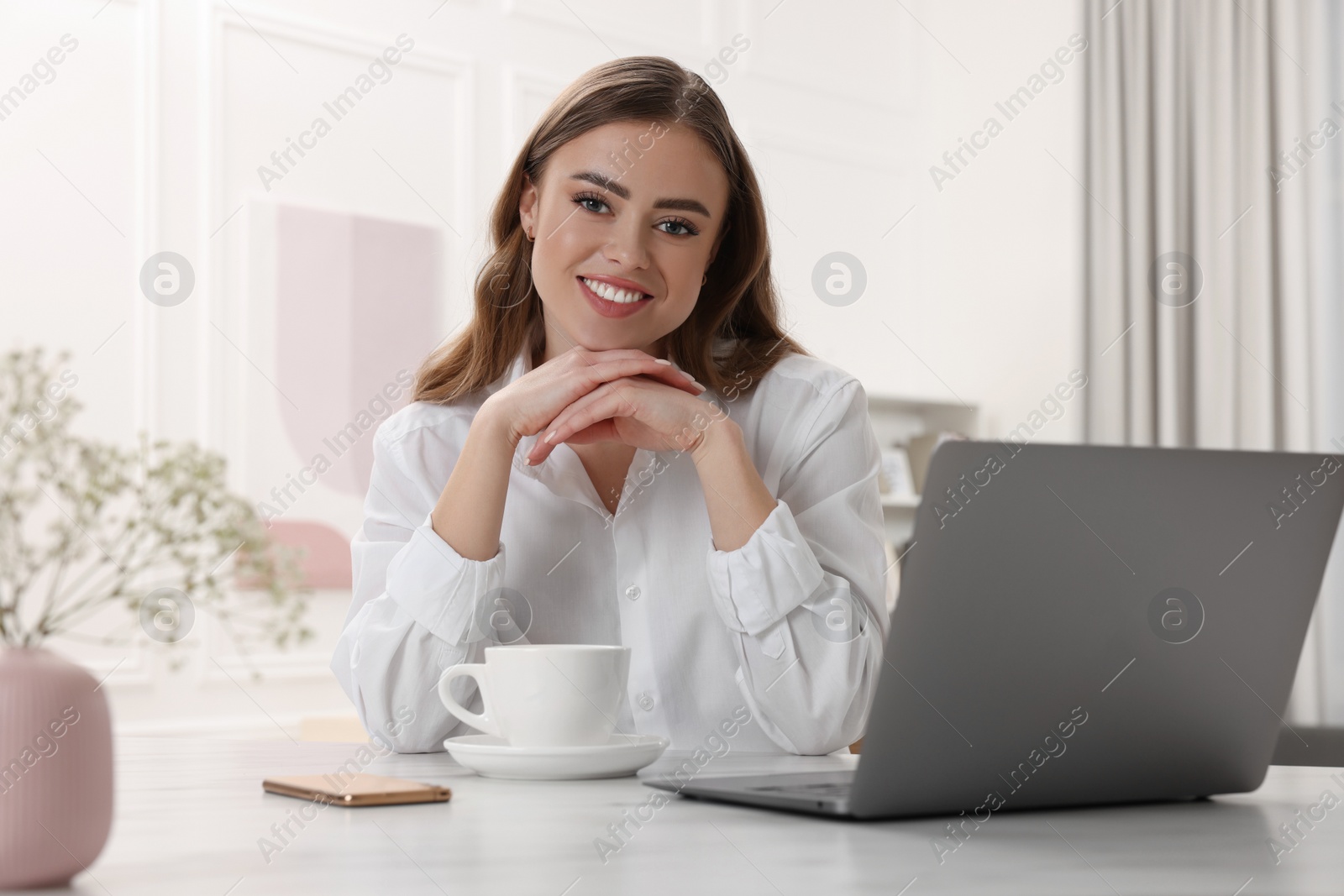 Photo of Happy woman with laptop at white table in room