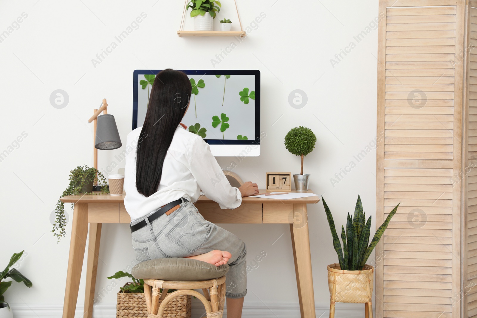 Photo of Young woman working at table in light room, back view. Home office