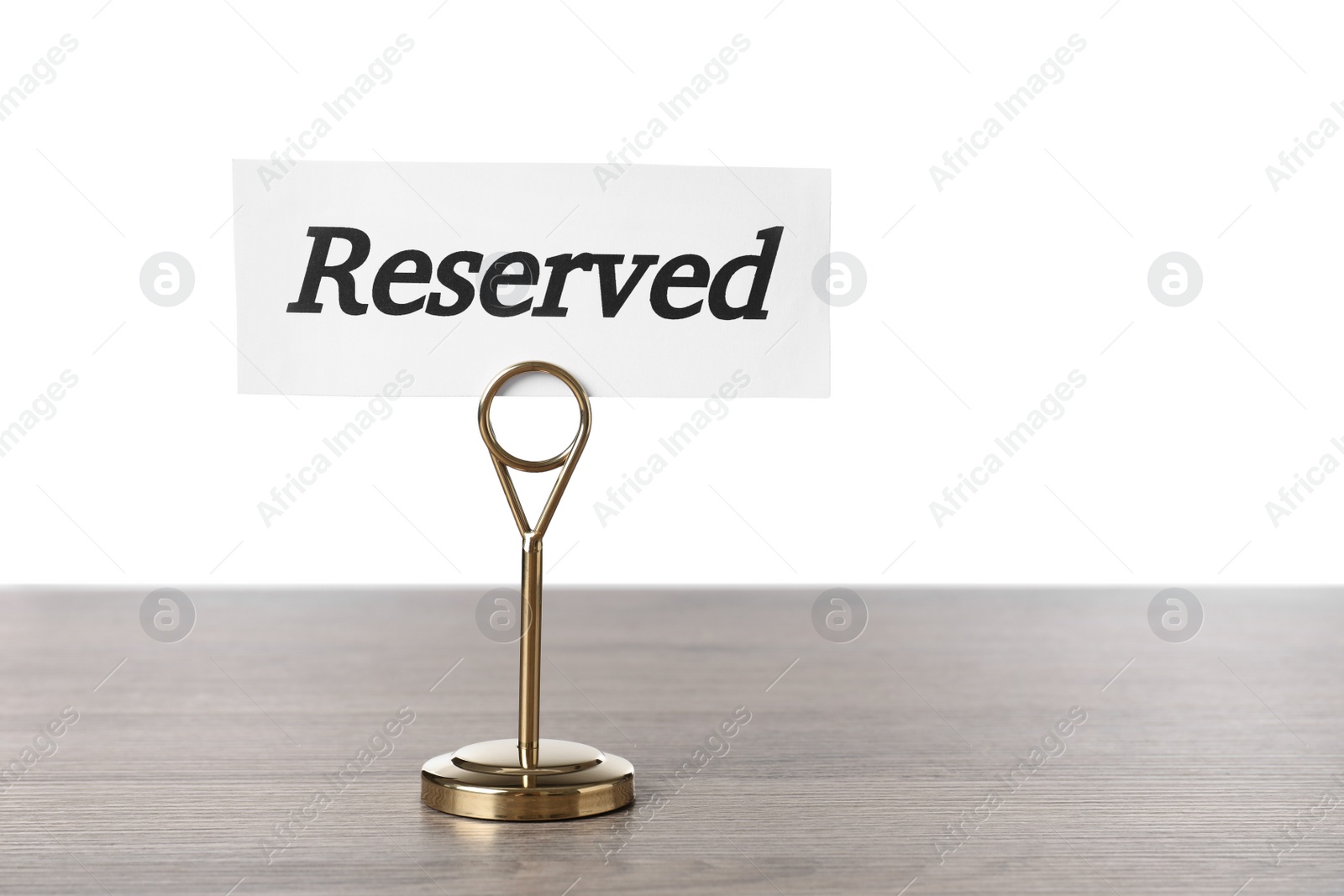 Photo of Elegant sign Reserved on wooden table against white background, space for text