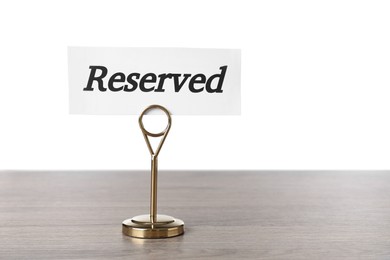 Photo of Elegant sign Reserved on wooden table against white background, space for text
