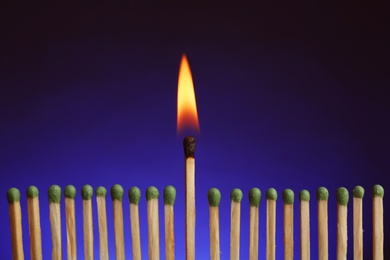 Photo of Burning match among others on color background. Difference and uniqueness concept