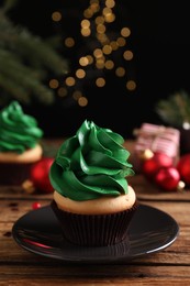 Photo of Delicious cupcake with green cream and Christmas decor on wooden table