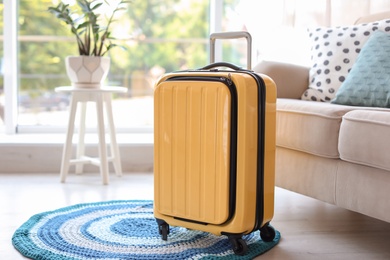 Photo of Bright yellow suitcase packed for journey at home