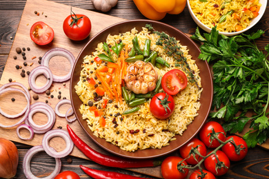 Photo of Flat lay composition with tasty rice pilaf on wooden table