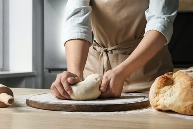 Photo of Female baker preparing bread dough at table, closeup