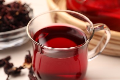 Cup of delicious hibiscus tea on white table, closeup