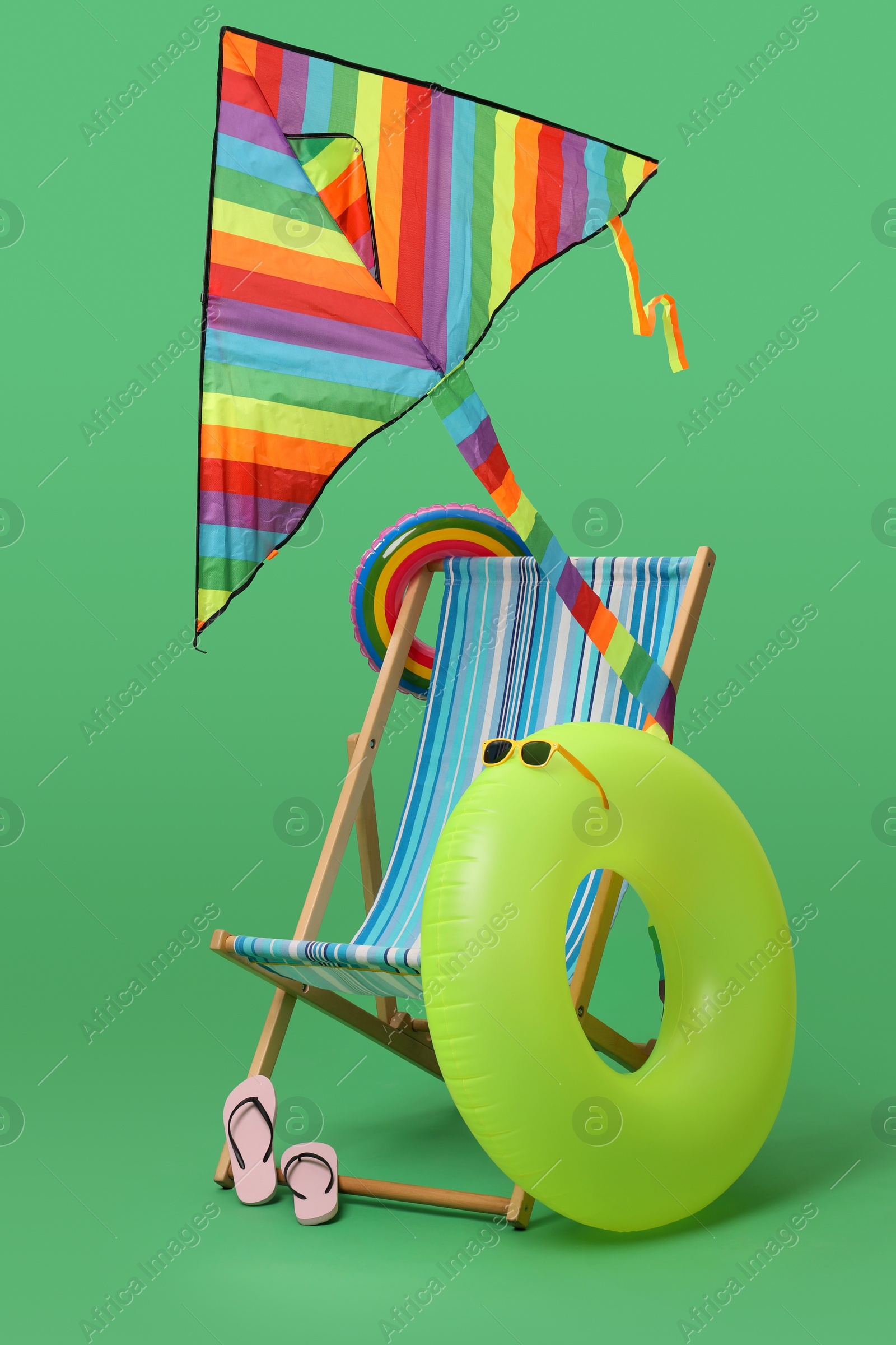 Deck chair, kite and beach accessories on green background. Summer vacation Photo of Deck chair, kite and beach accessories on green background. Summer vacation