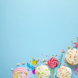 Flat lay composition with cupcakes on light blue background, space for text. Birthday party