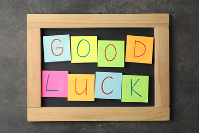 Photo of Notes with phrase GOOD LUCK on grey stone background, top view
