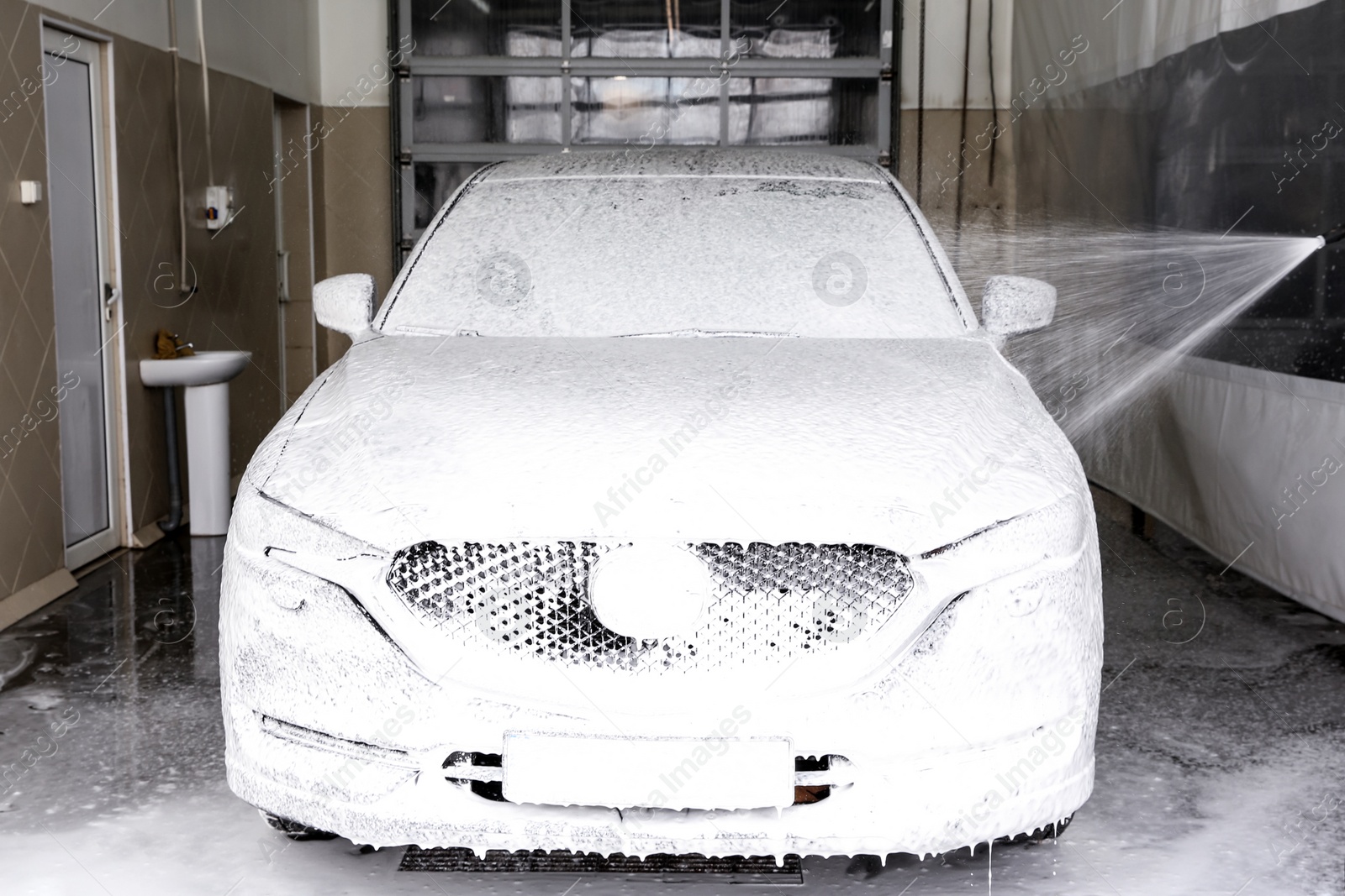 Photo of Cleaning automobile with high pressure water jet at car wash